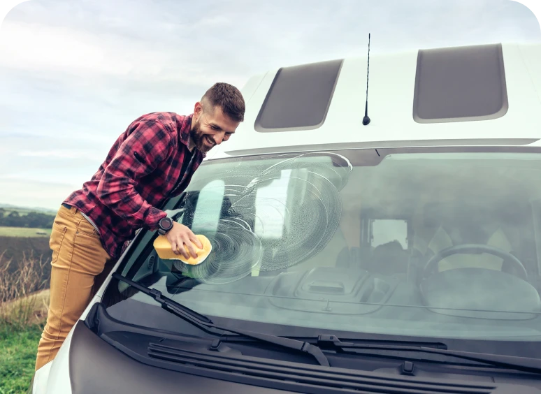 Person washing vehicle window with sponge